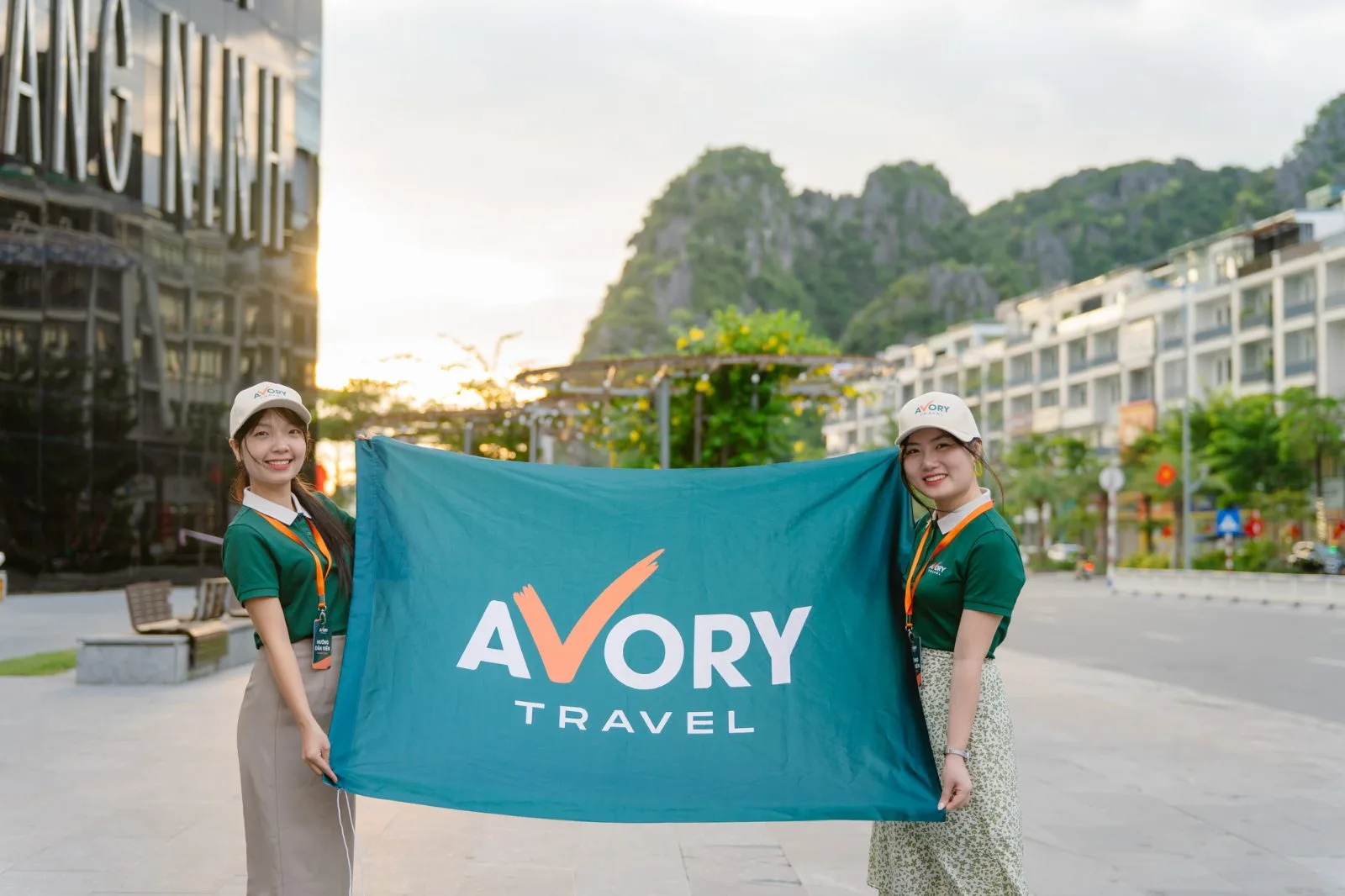 Hai hướng dẫn viên căng lá cờ lớn Avory Travel trên phố biển Hạ Long