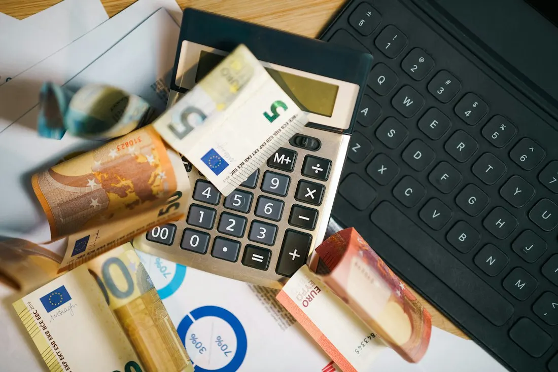 Máy tính cầm tay và tiền euro trên bảng biểu chi phí